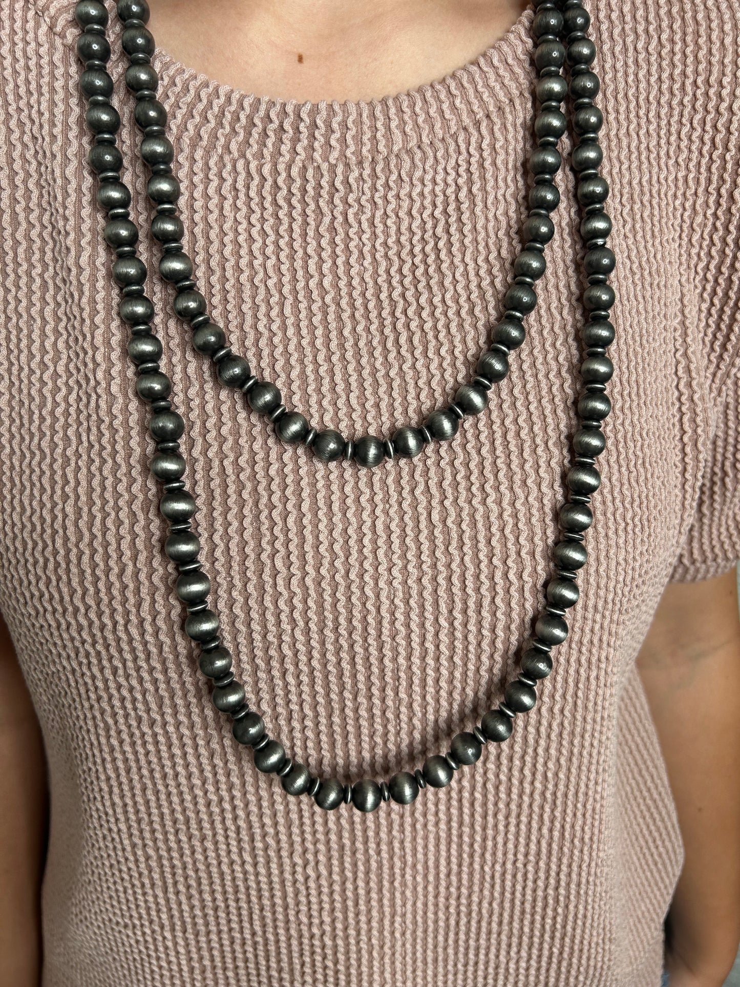 NAVAJO beaded necklace draped over a textured beige fabric surface