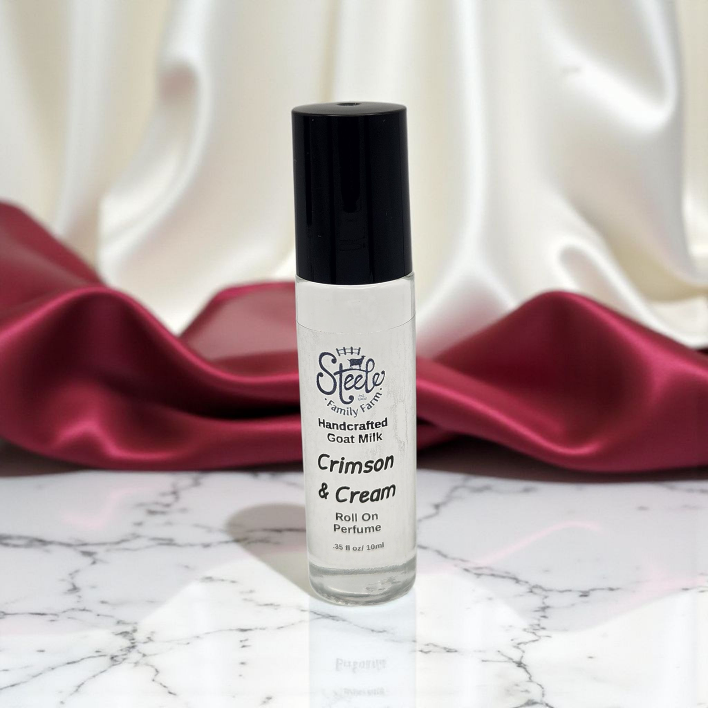 Roll-on perfume bottle labeled 'Crimson & Cream' on a marble surface with red fabric in the background.