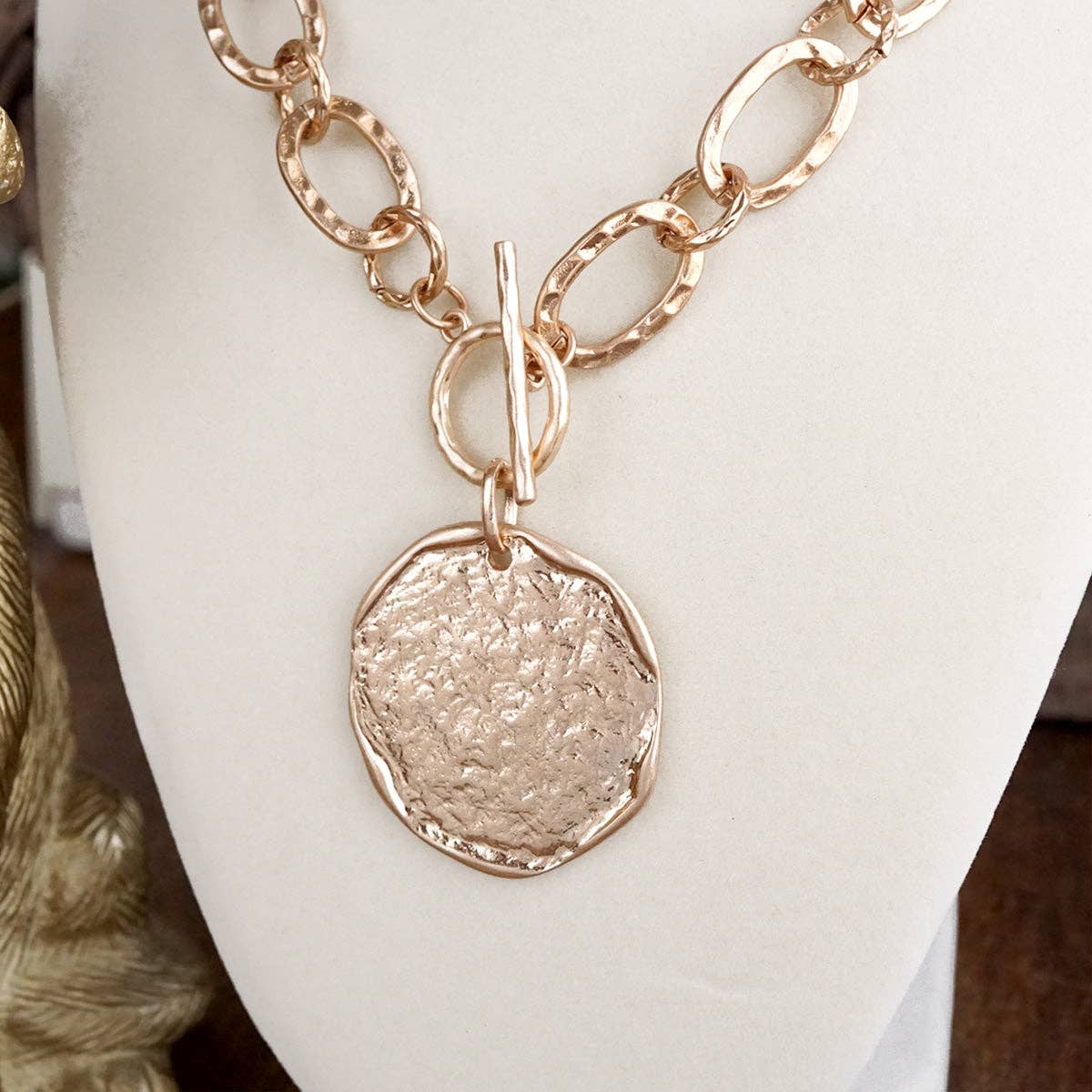 hammered gold disk with toggle closure necklace on a bust