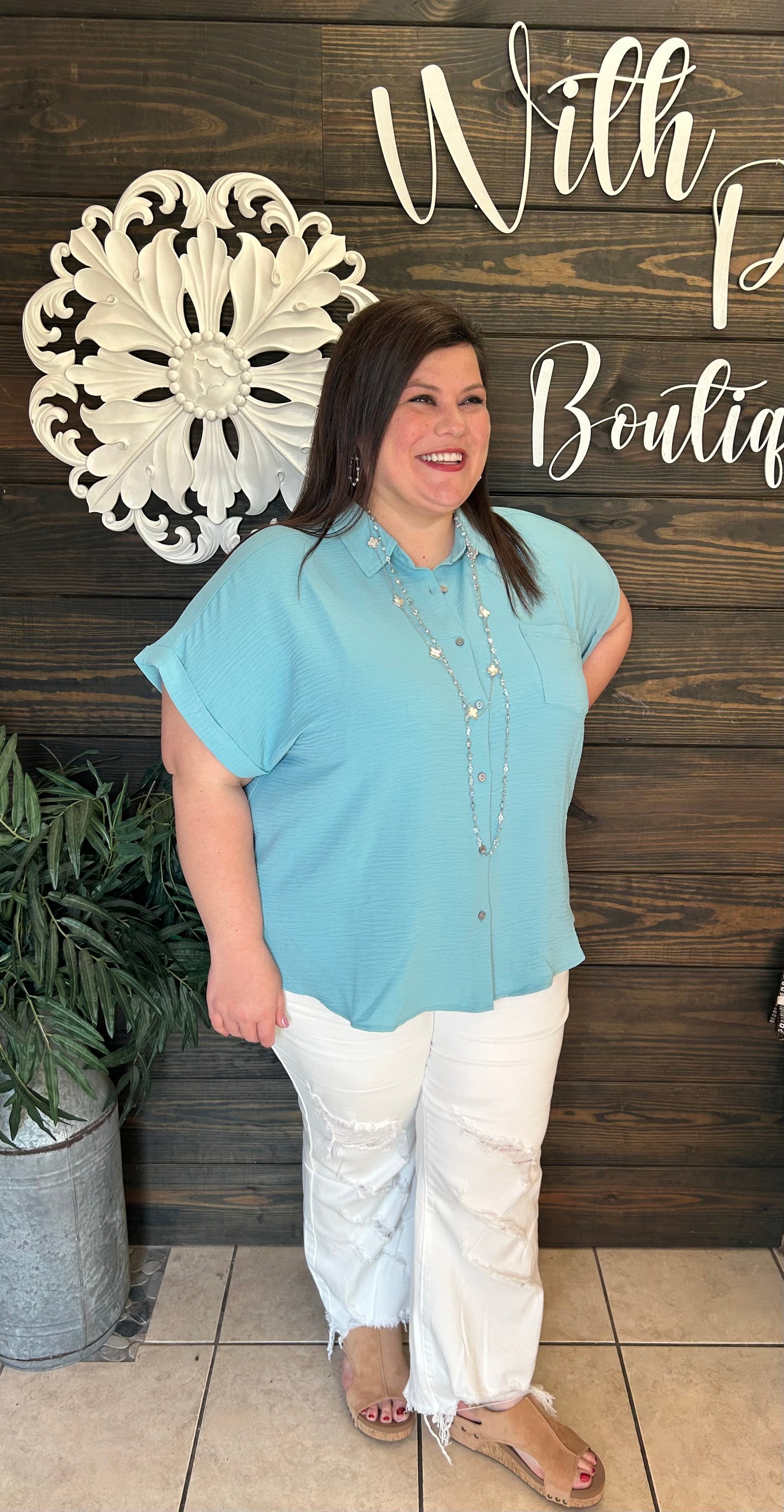 Teal colored relaxed fit button down with front pocket, hi low hem, side slit, air flow material, short sleeves with small, rolled cuff.