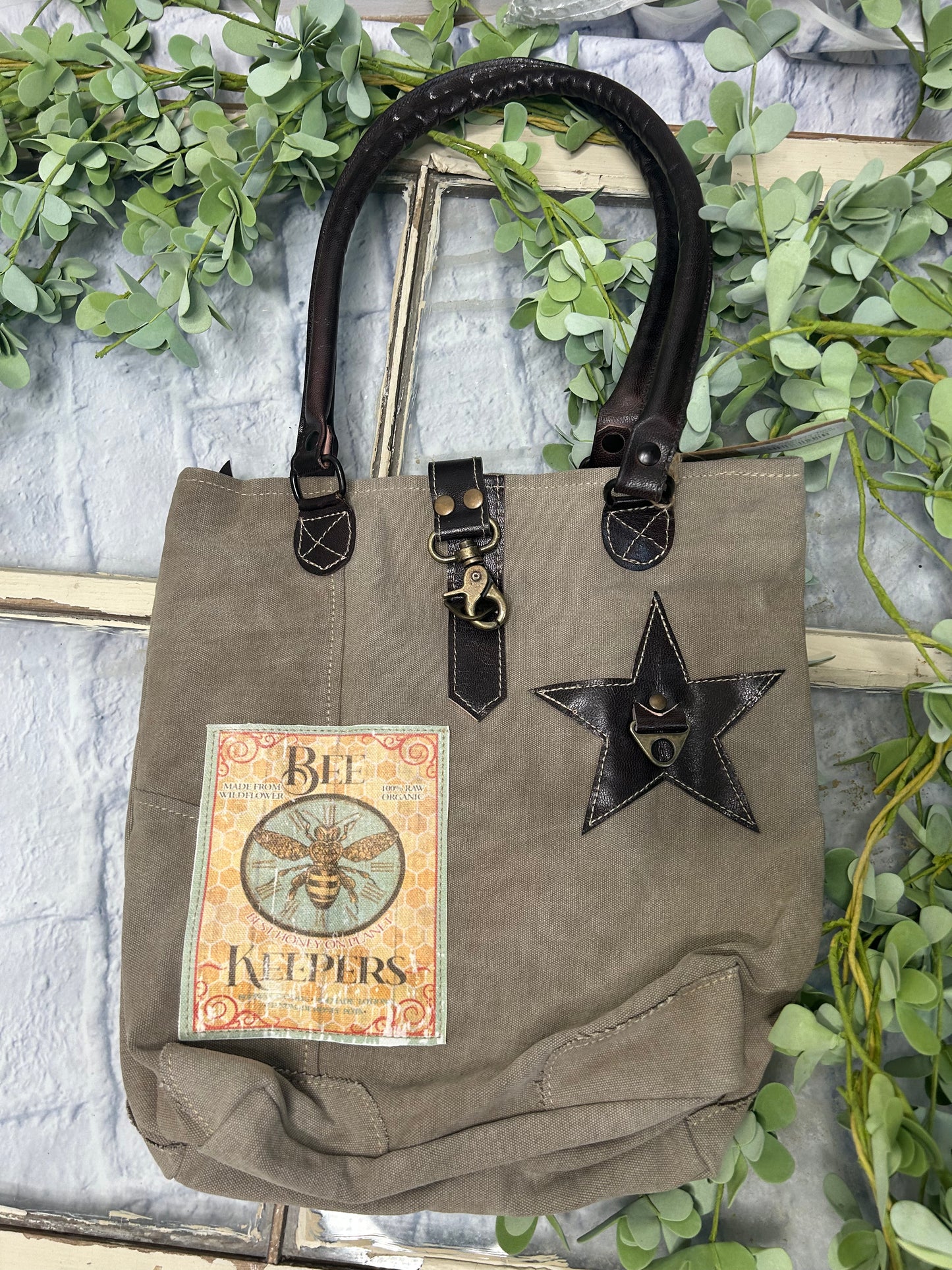 This uniquely charming tote is crafted from upcycled canvas for a vintage vibe. Attention to detail shows in the quality, including lobster claw clips and a back zippered pocket, three inside pockets, star applique and bee patch inlay! (Bee-cause who doesn't want a bag with buzz?)
Designed & Manufactured in USA/Hand Crafted bags made from upcycled canvas
such as repurposed military tents & more /approx:10 x 14 x 3.5