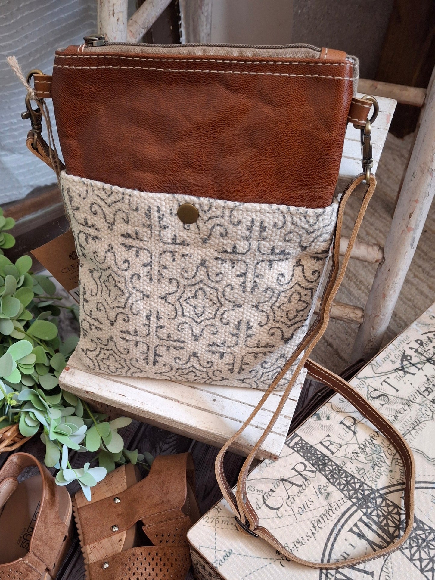 This stylish crossbody can be dressed up or down, making it super versatile! This bag features a stylish pattered front trimmed in leather. Its snap front pocket makes it convenient to carry your keys (or whatever) without digging! This crossbody has a vintage blue and white stripe lining, two outside pockets, and an adjustable shoulder strap. 