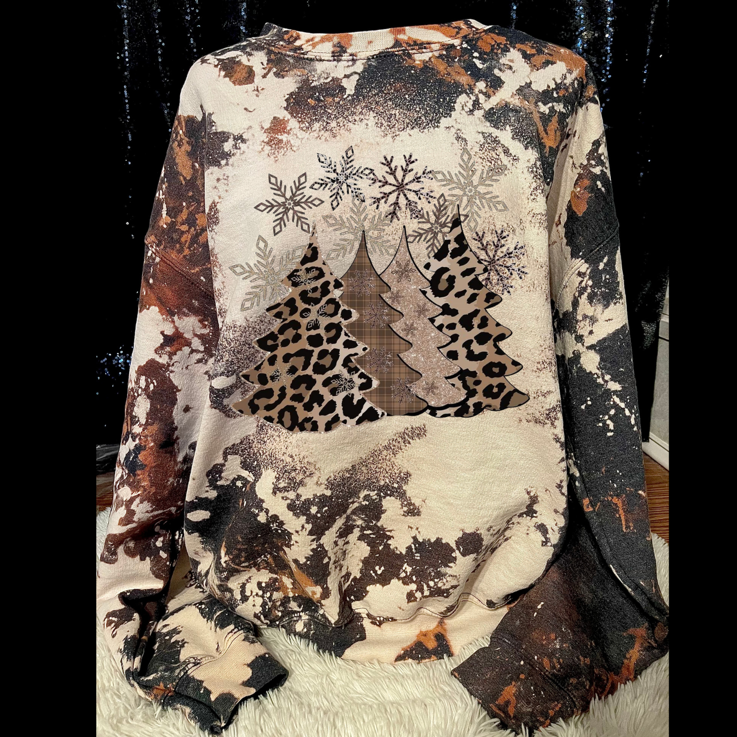 Sweater with snowflake, tree, and leopard print design on a black background