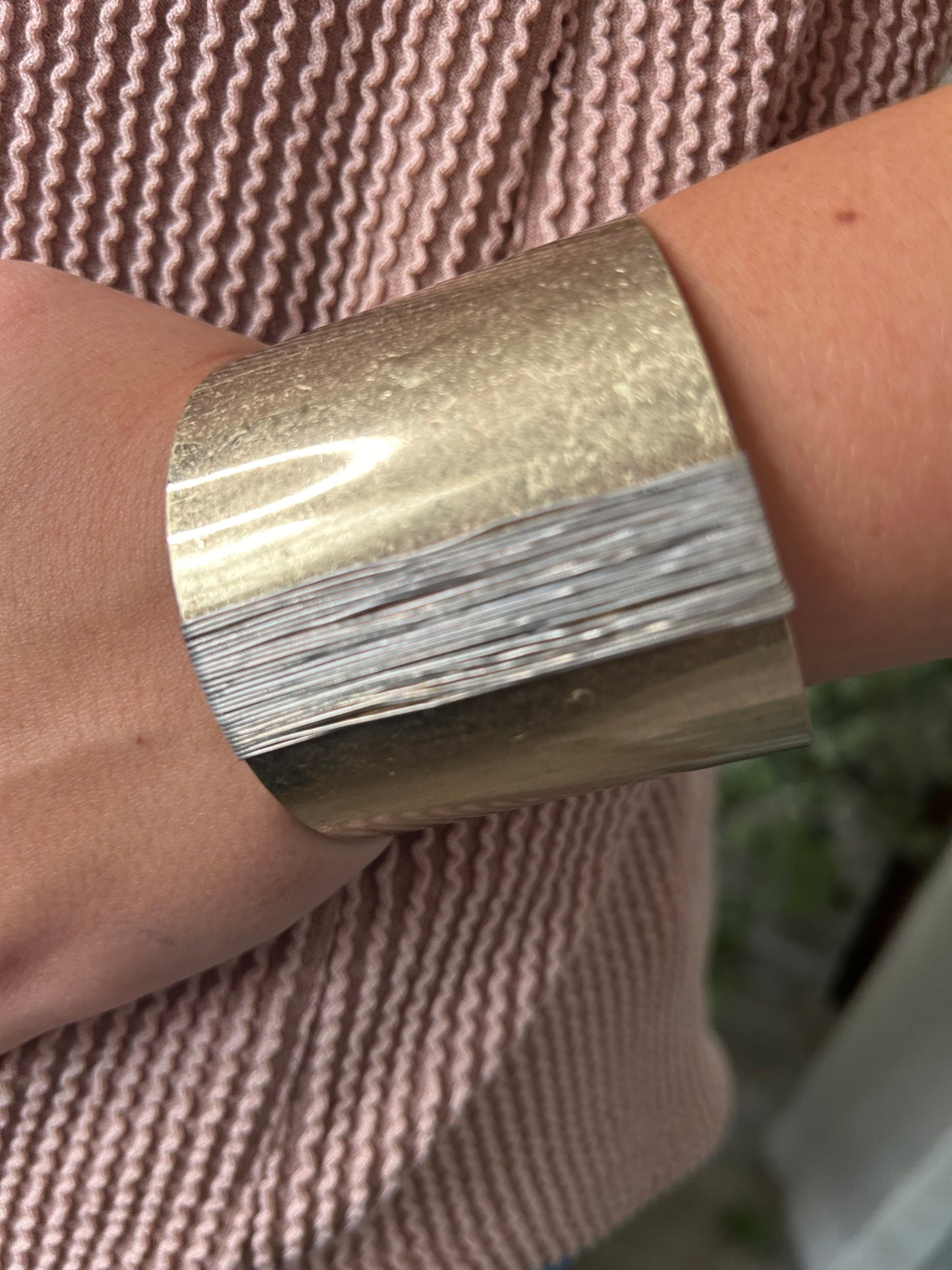 wide gold cuff bracelet with silver wire on arm