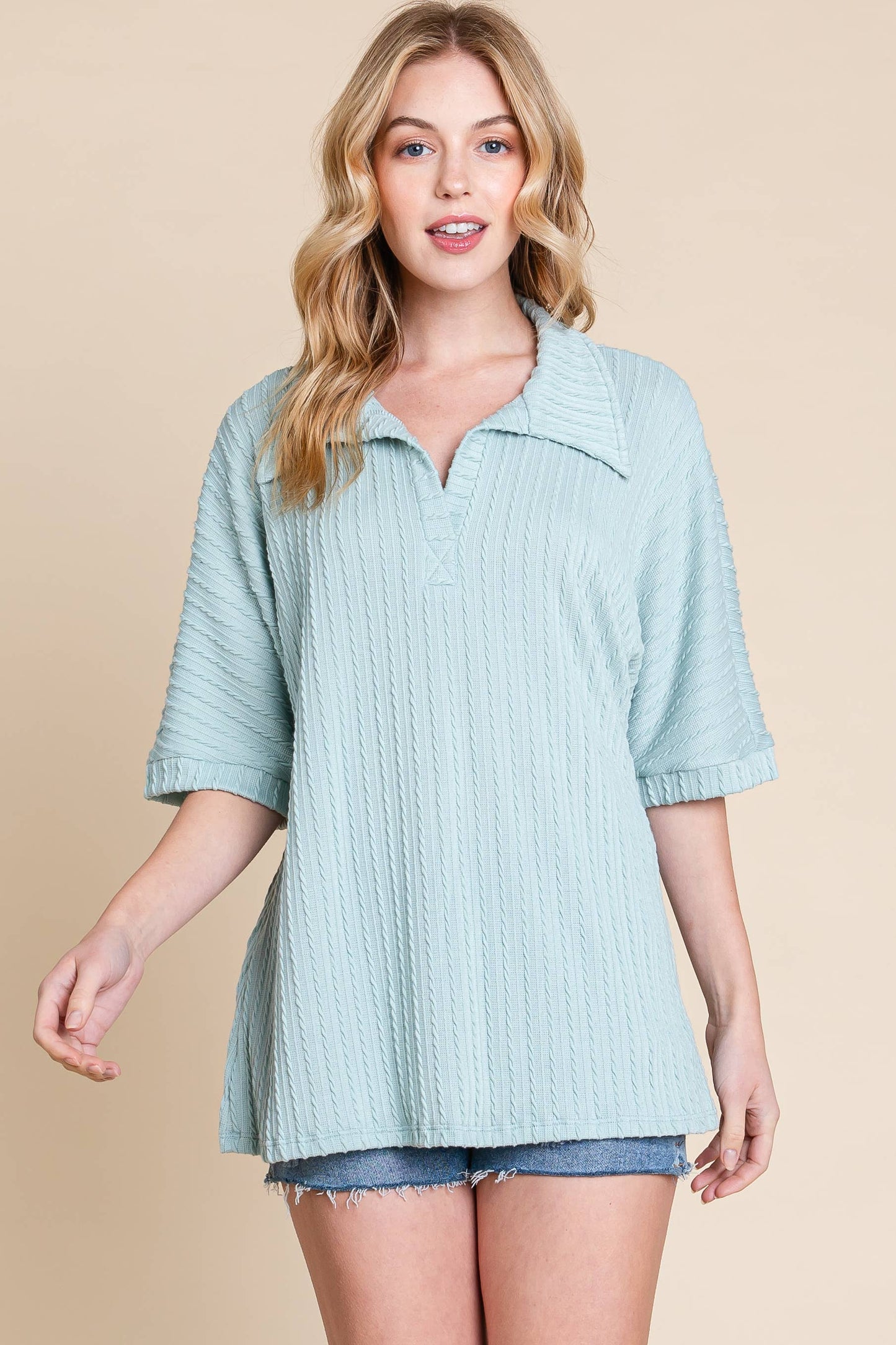 woman wearing a dusty mint polo top with shorts