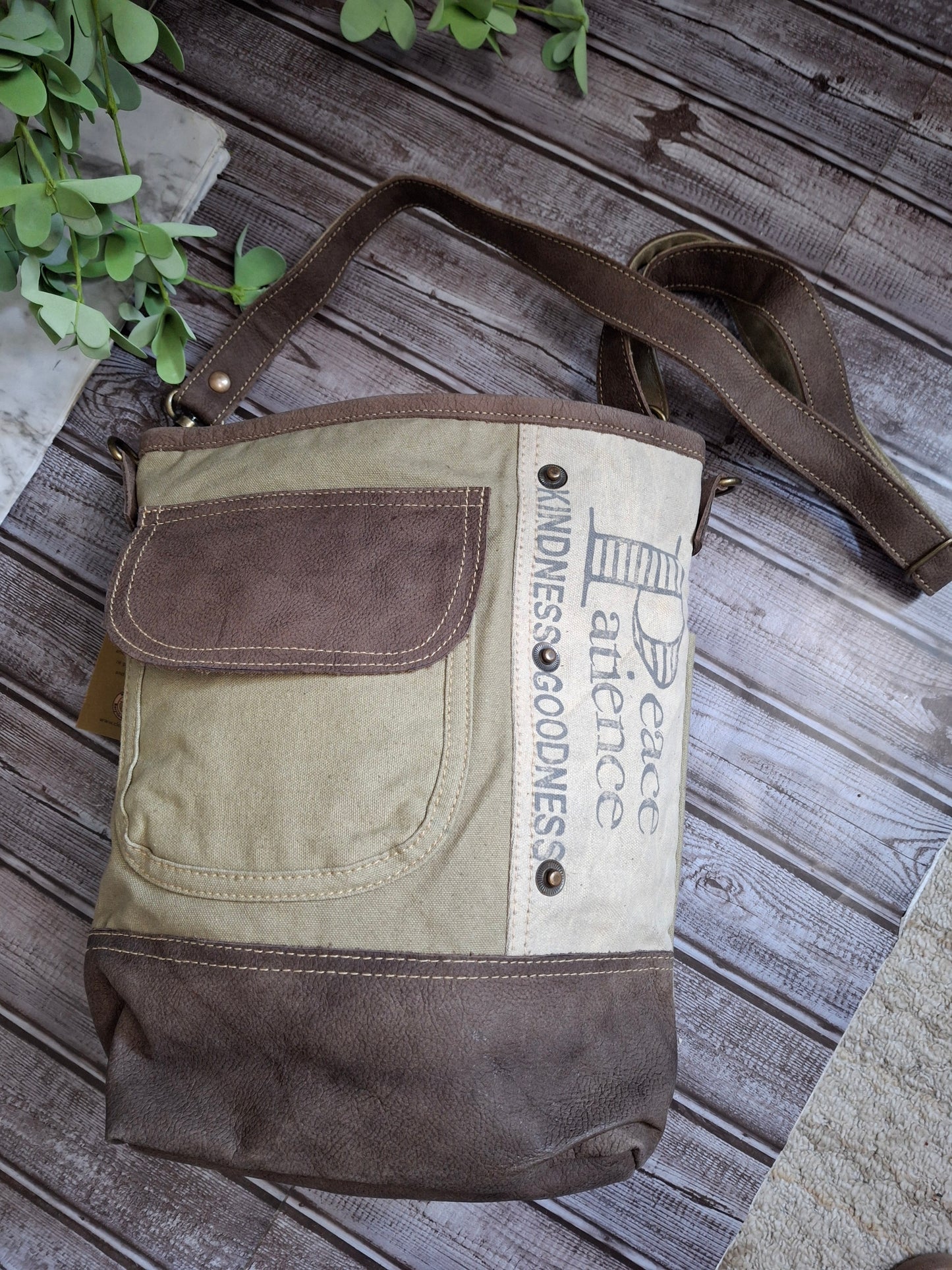  “Peace, Patience, Kindness, Goodness” are printed on the copper-studded panel of this rustic bag. Vintage blue and white stripe lining, three inside pockets, two outside pocket, shoulder strap.
Designed & Manufactured in USA/Hand Crafted