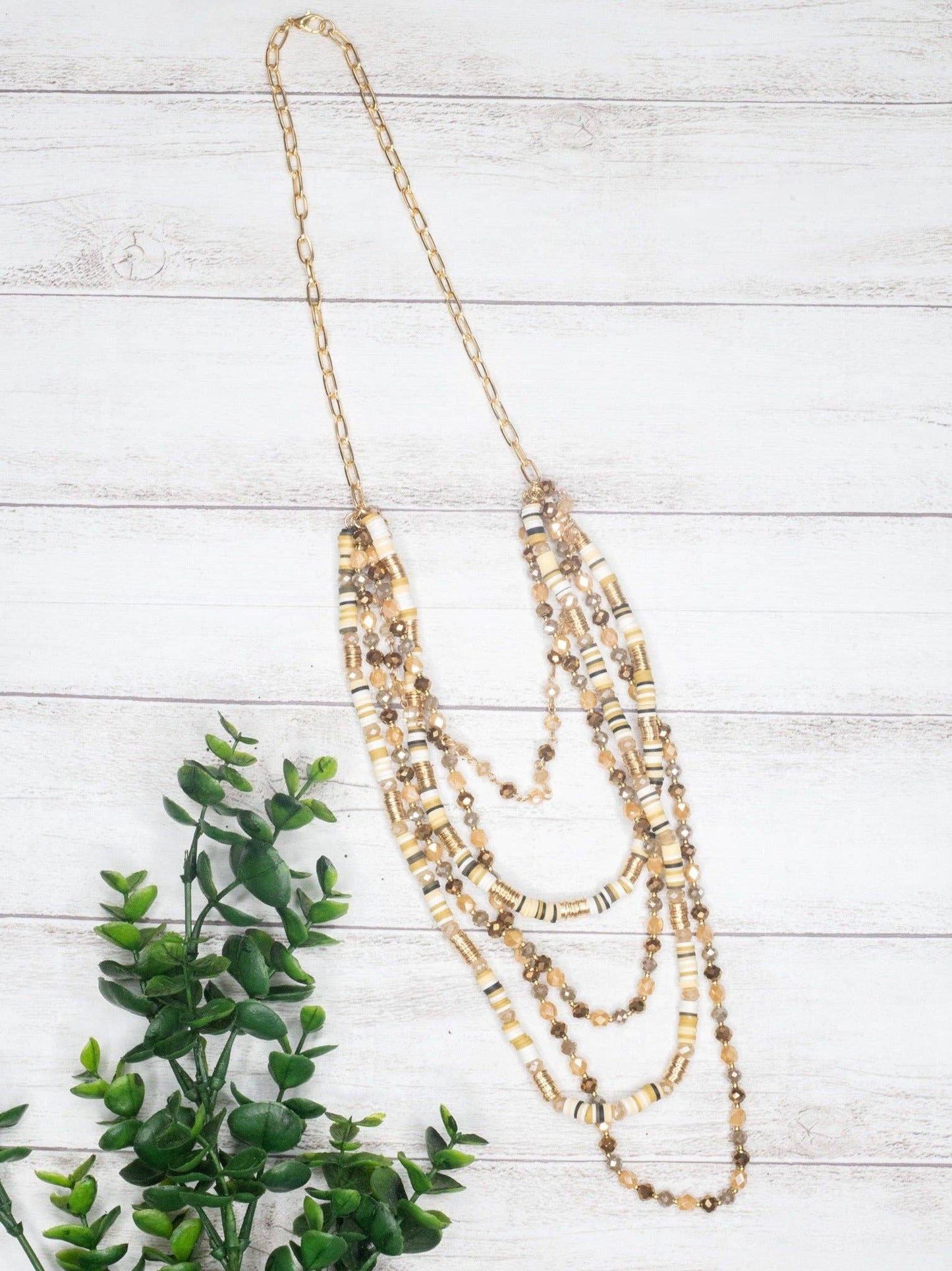 Tan Shell Beads With Mixed Crystal Beads Gold Link Chain Necklace - layred neceklace in shades of tans and ambers on a white wall