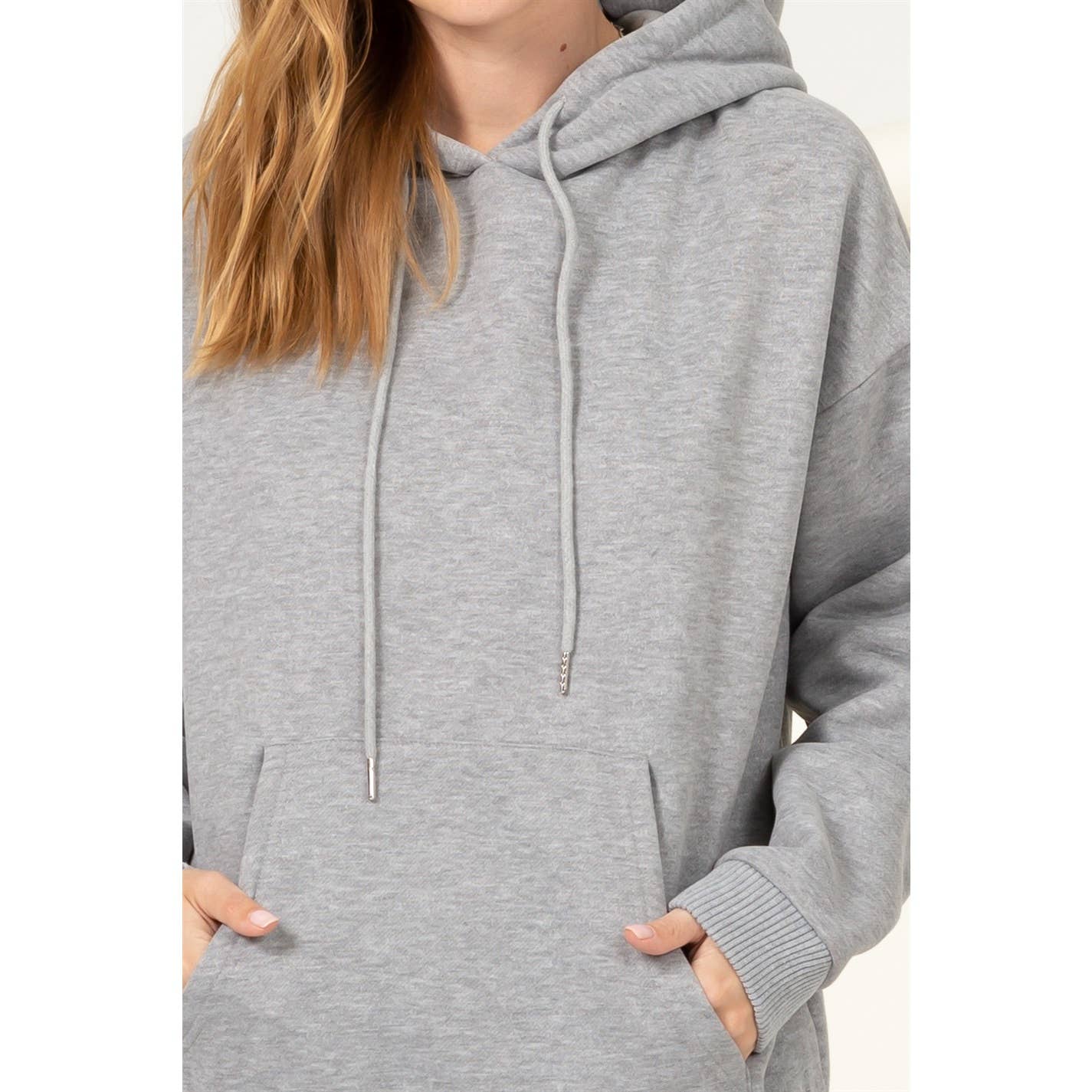 Person wearing a gray hoodie with a plain background