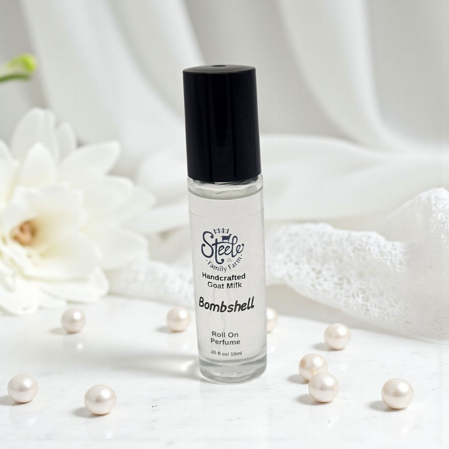 Roll-on perfume bottle labeled 'Bombshell' by 'My Steele Family Farm' on a white background with pearls and flowers.