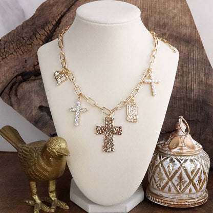 Gold necklace with cross pendant on a mannequin bust, surrounded by decorative items.