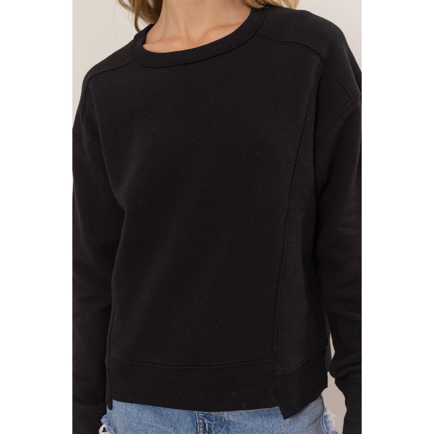 Black sweatshirt worn by a person on a plain background