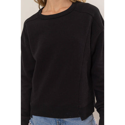 Black sweatshirt worn by a person on a plain background