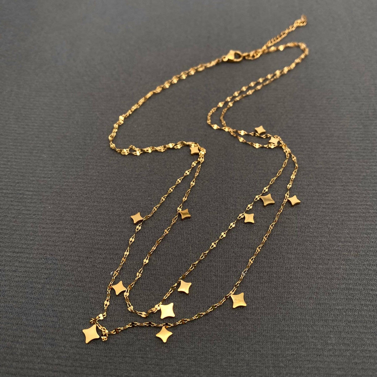 Gold necklace with star pendants on a dark gray background