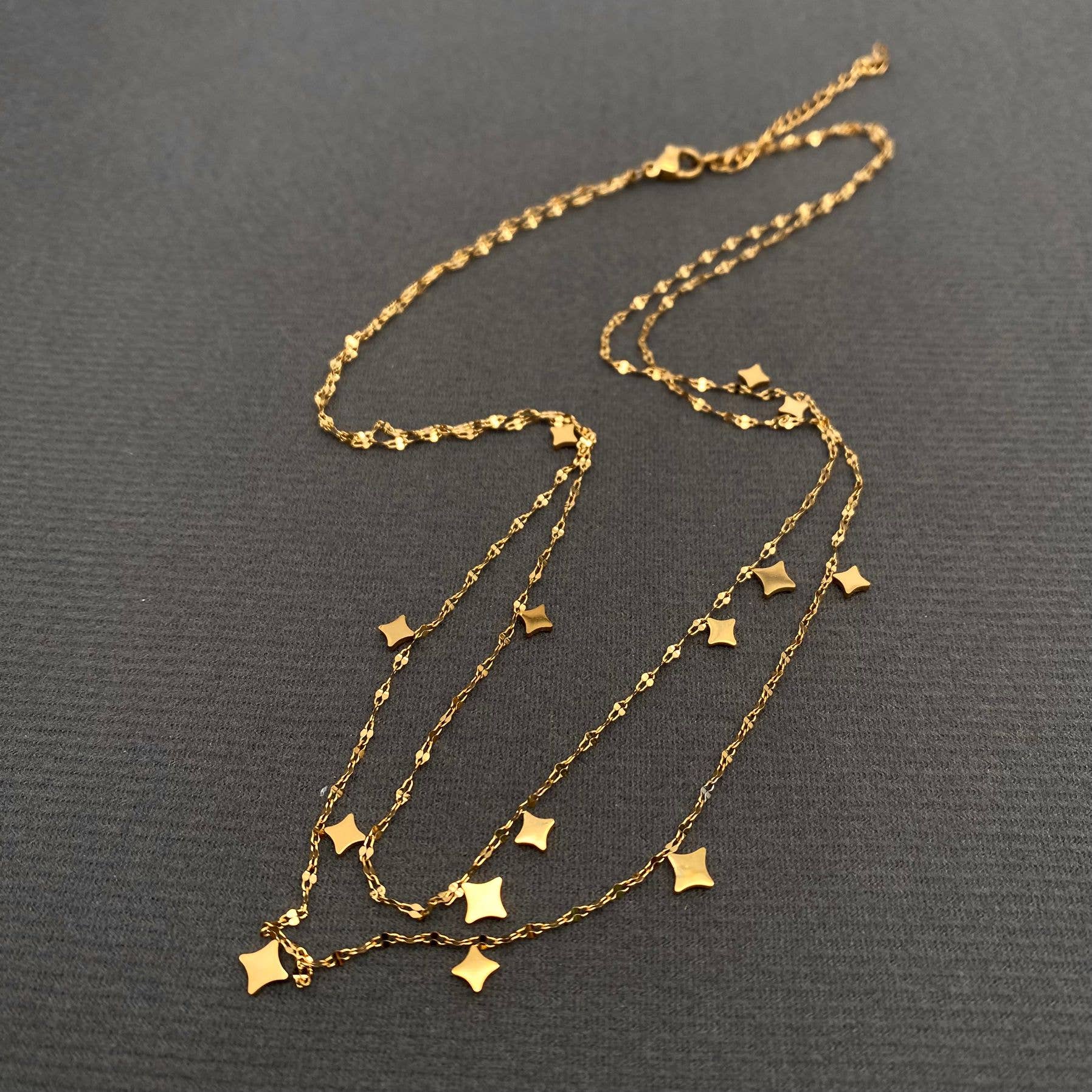 Gold necklace with star pendants on a dark gray background