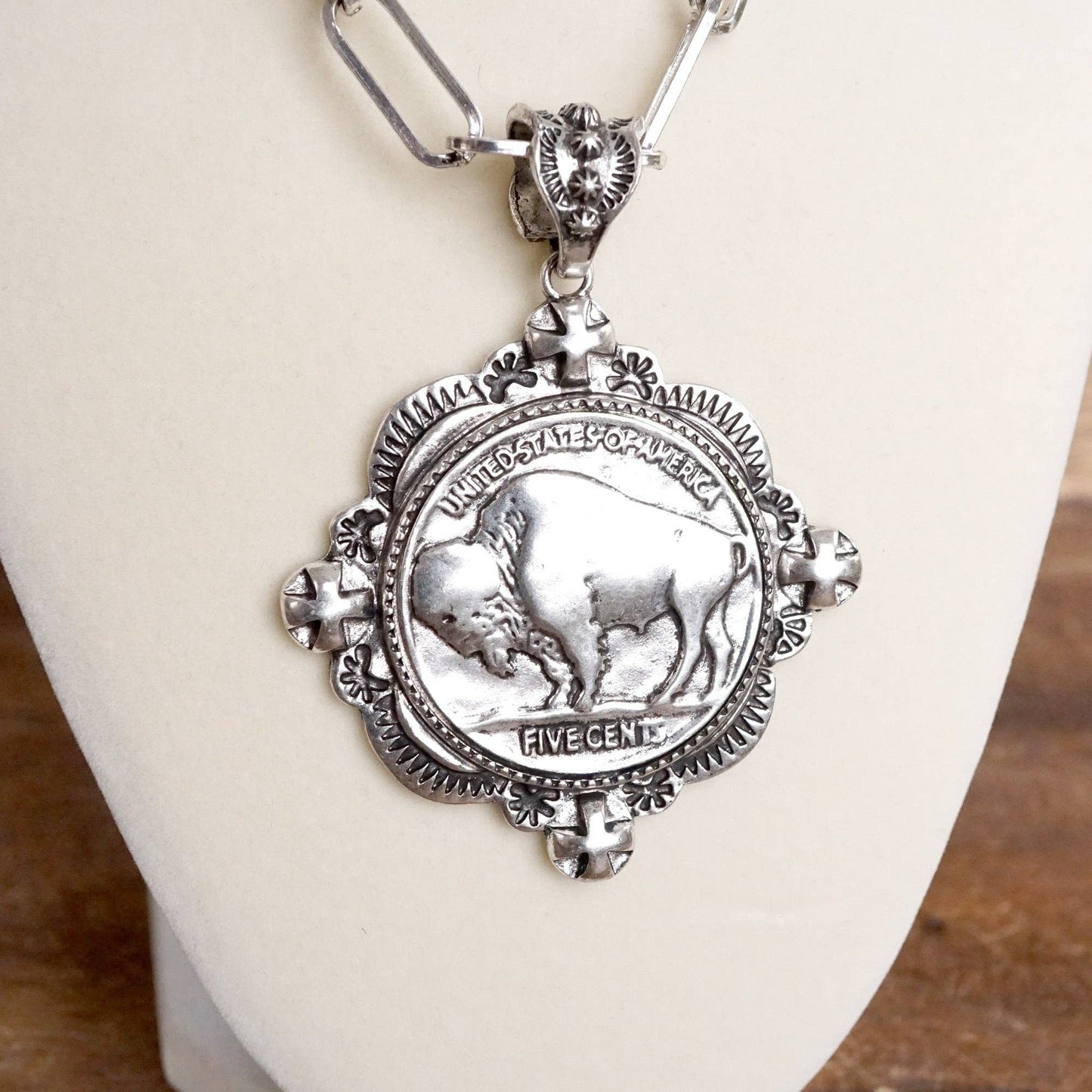 Silver necklace with a coin pendant featuring a buffalo on a white stand.