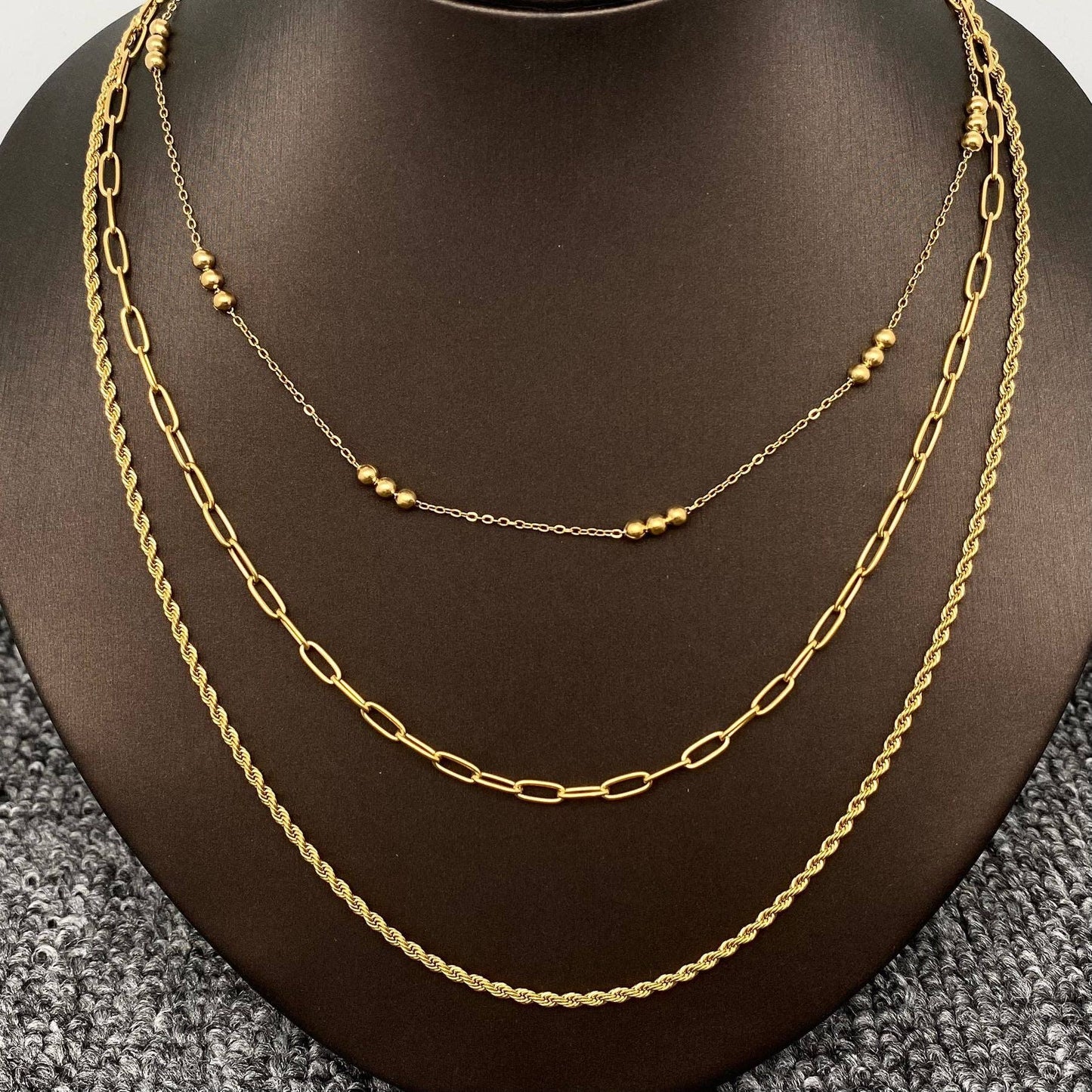 Gold 3 piece layered chain necklace on a mannequin neck