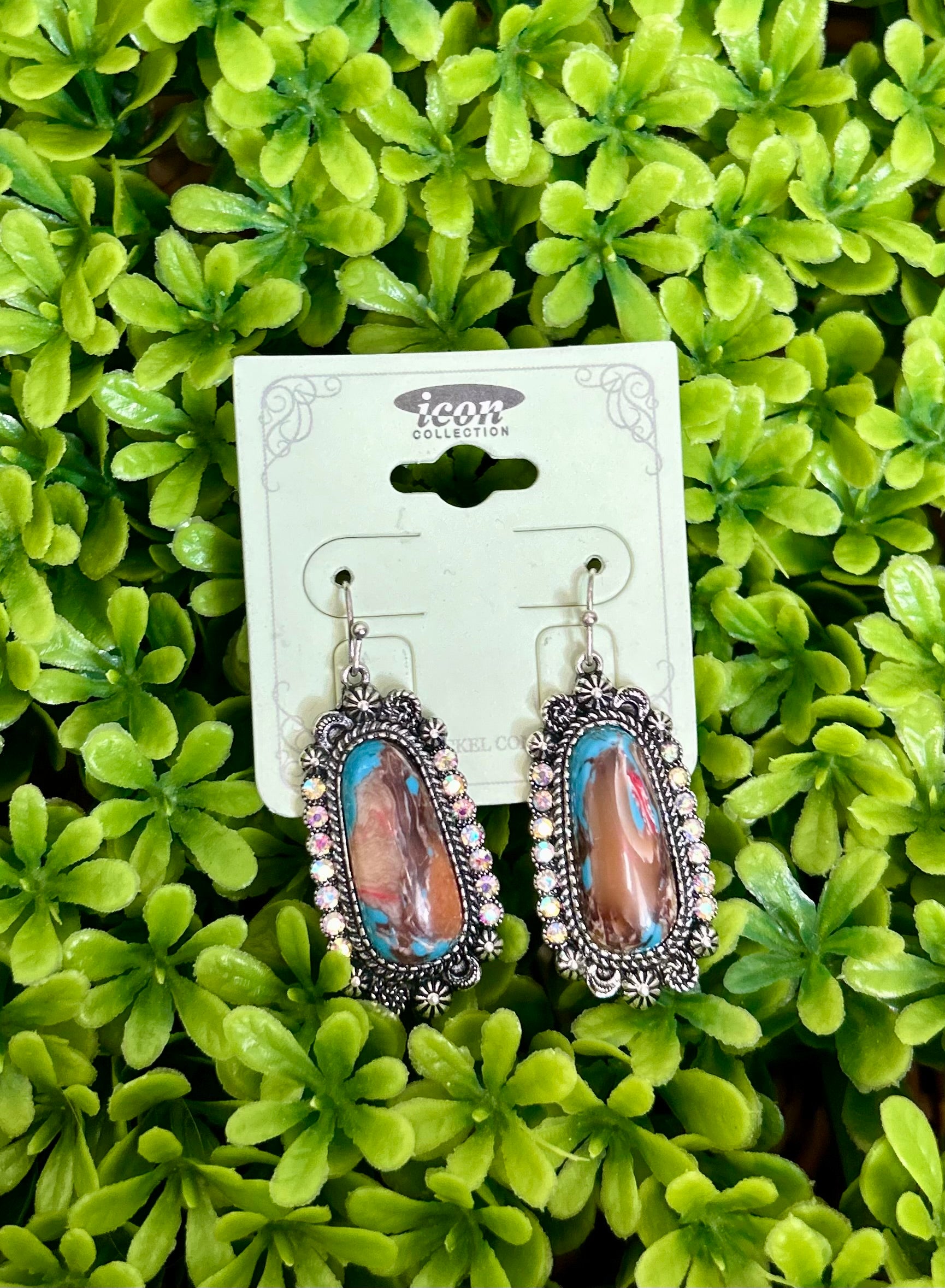 Pair of colorful earrings on a card with a green leafy background