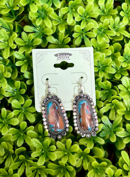 Pair of colorful earrings on a card with a green leafy background