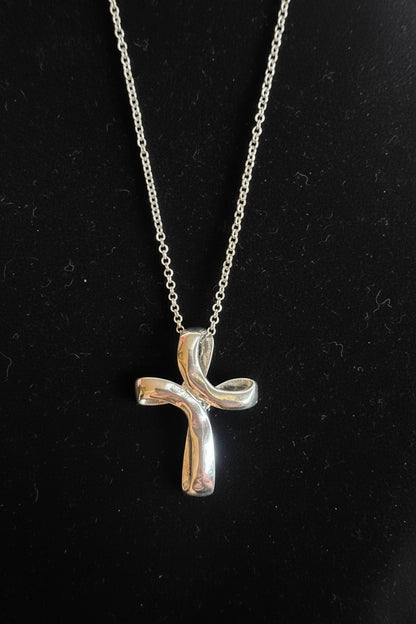 A silver wave cross necklace design on a black background