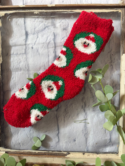 Red knitted stocking with Santa Claus faces on a textured surface