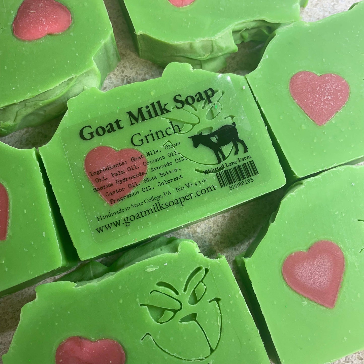 Green Grinch goat milk soap with heart designs and a visible label on a textured surface.
