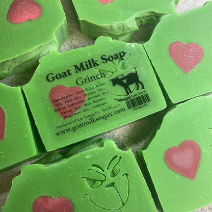 Green Grinch goat milk soap with heart designs and a visible label on a textured surface.