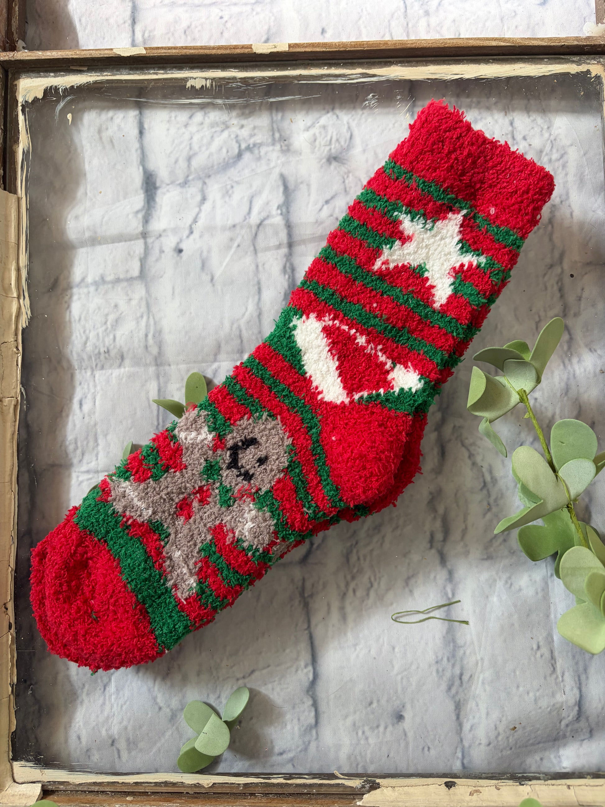 Red knitted Christmas stocking with green and white patterns on a textured surface.