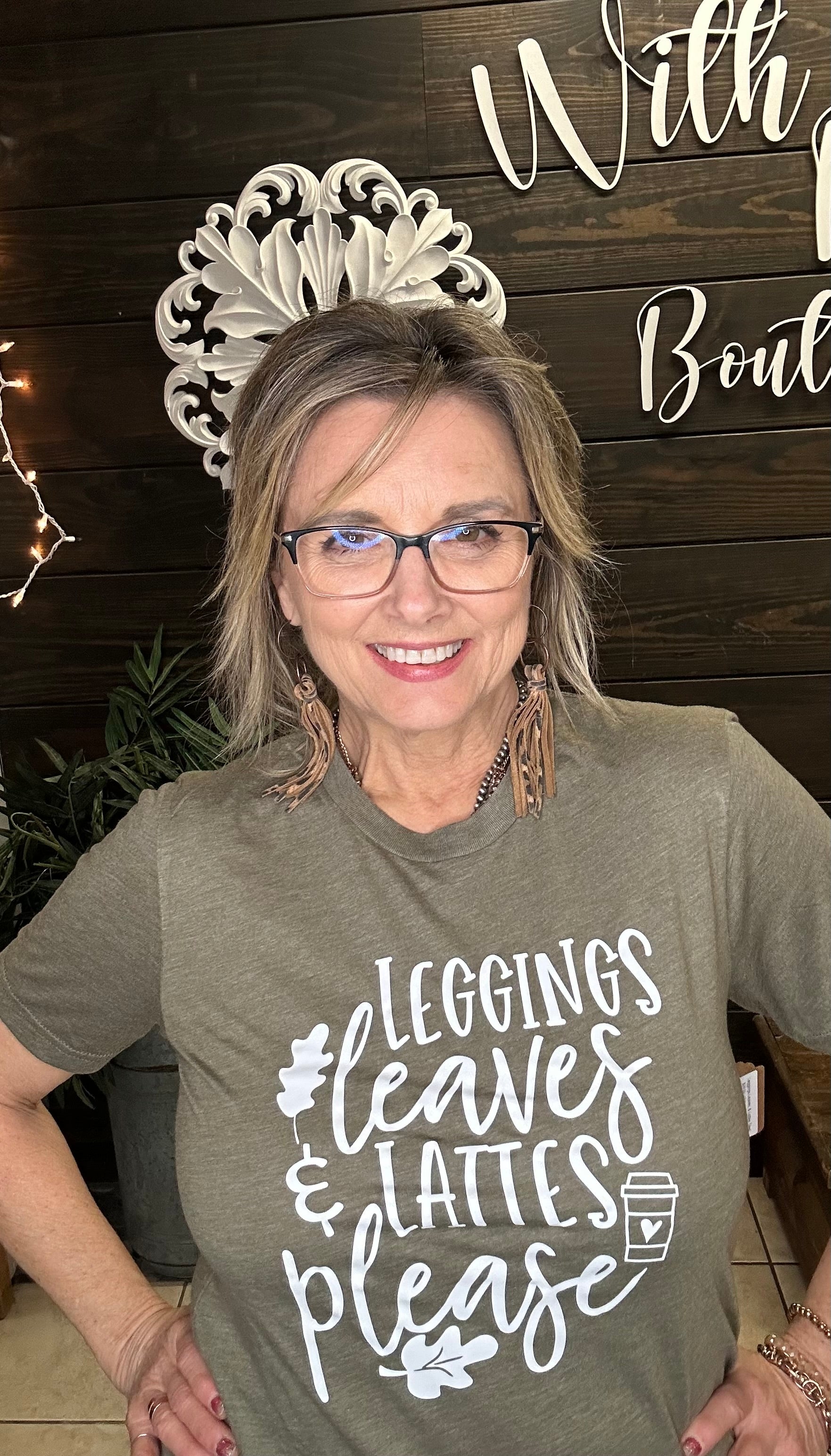 Woman wearing a green t-shirt with text, standing in front of a wooden wall with decorative elements.