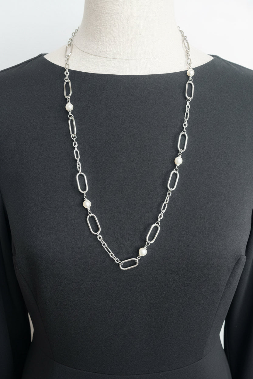 A silver and pearl chain neclace on a black shirt