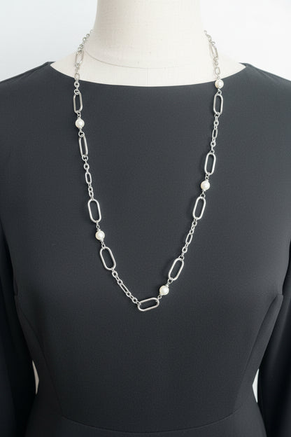 A silver and pearl chain neclace on a black shirt