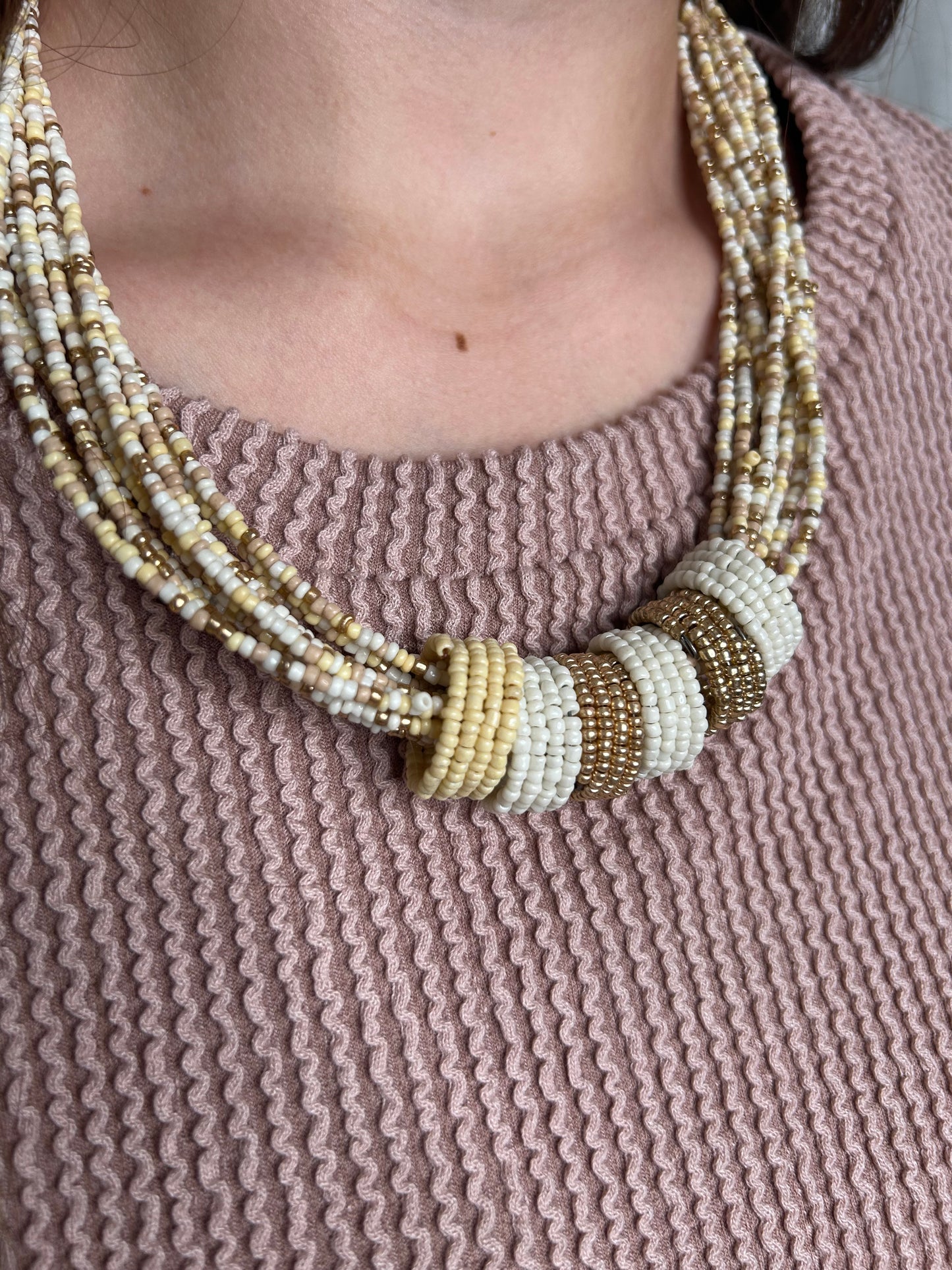 Close-up of a person wearing a beaded bracelet on a textured pink background