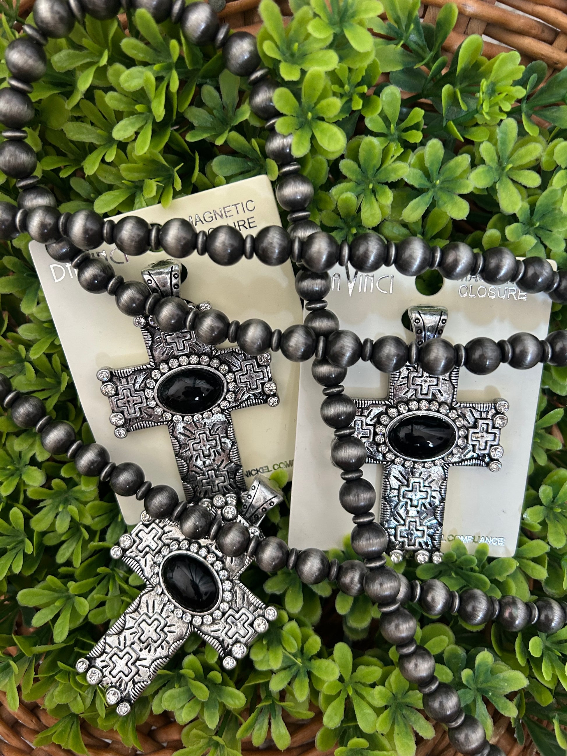 black etched cross pendant with navajo beads on grass background