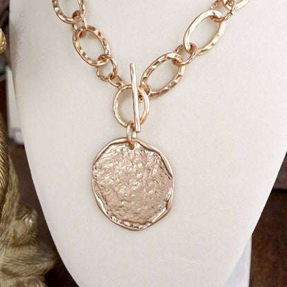 hammered gold disk with toggle closure necklace on a bust