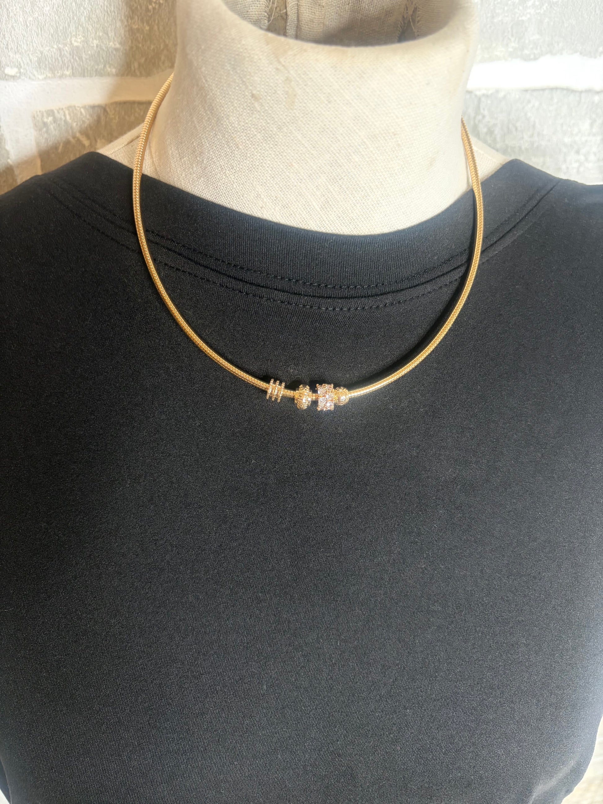 Gold necklace on a mannequin with a plain background