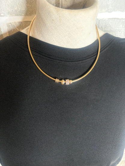 Gold necklace on a mannequin with a plain background