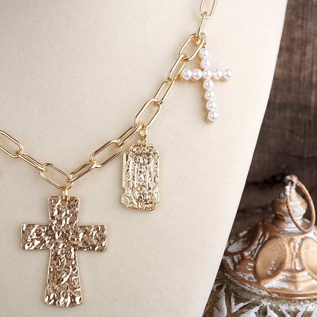 Gold chain necklace with cross pendants on a neutral background