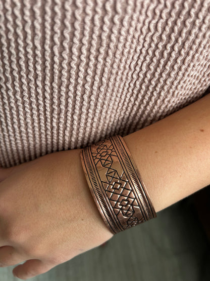 Copper bracelet on a wrist against a textured fabric background