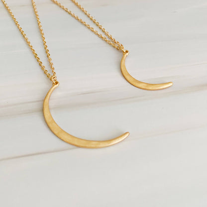 Gold crescent moon necklace on a white background