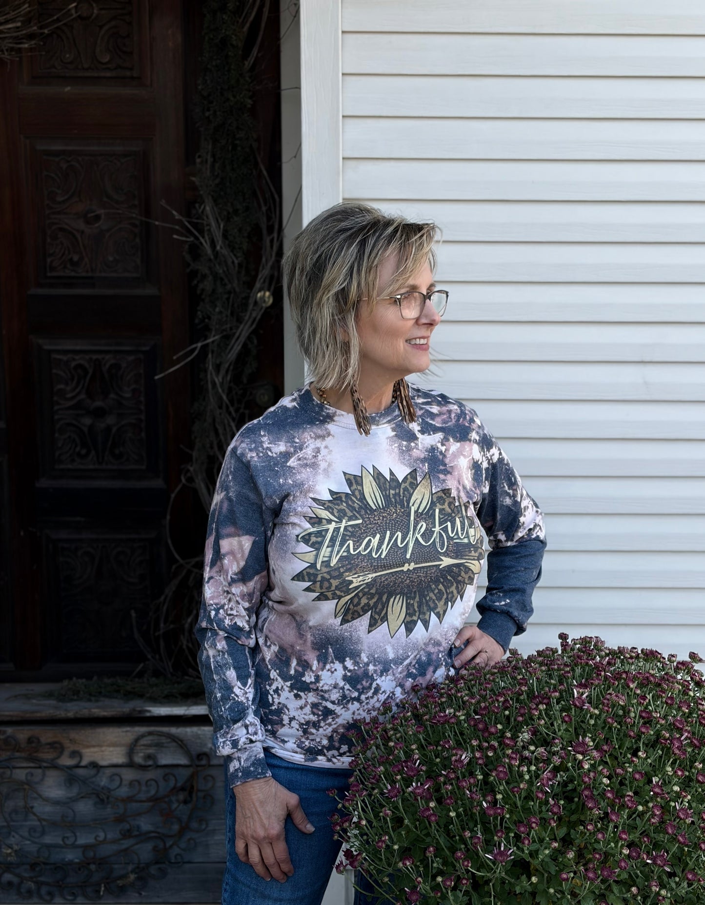 Person wearing a tie-dye long sleeve with 'Thankful' design standing outdoors.