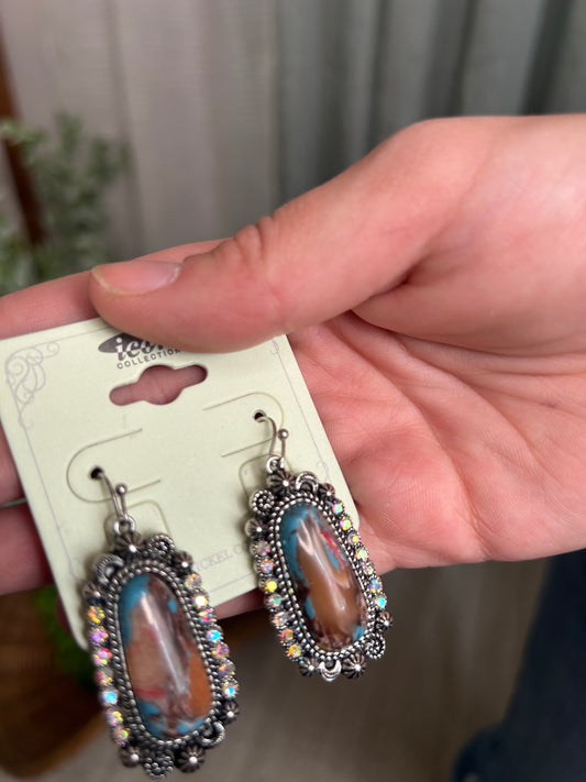 pair of beautiful stone and rhinestone earrings held by hand