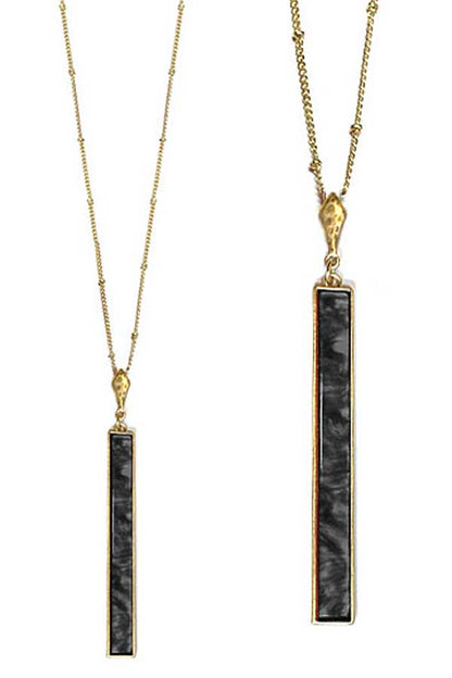 Gold necklaces with black pendant stones on a white background