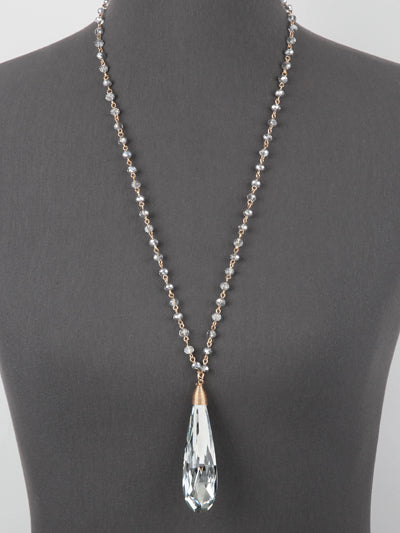 Necklace with a clear teardrop pendant on a mannequin against a gray background