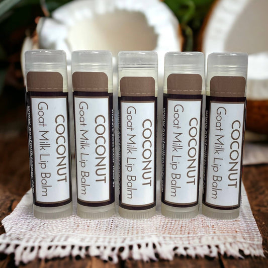 Five tubes of Coconut Goat Milk Lip Balm on a white doily with a blurred background.