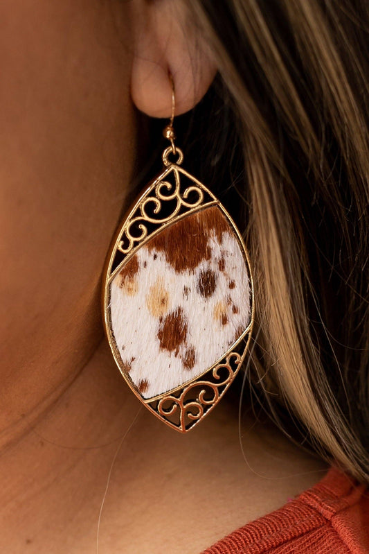 Cowhide Serenade: Gilded Gold Scroll Earrings with a Twist -on a womans ear
