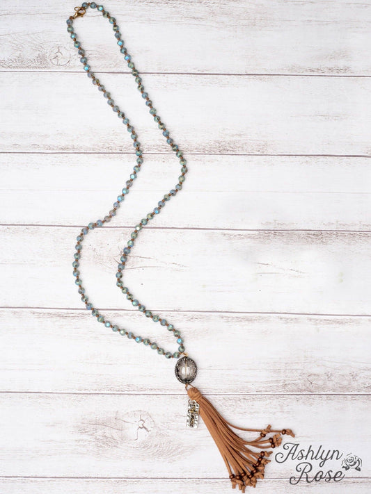 Necklace with tassel on a wooden surface, branded 'Ashlyn Rose'.