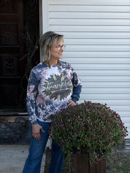 Woman wearing a 'Thankful' shirt in front of a large potted plant.