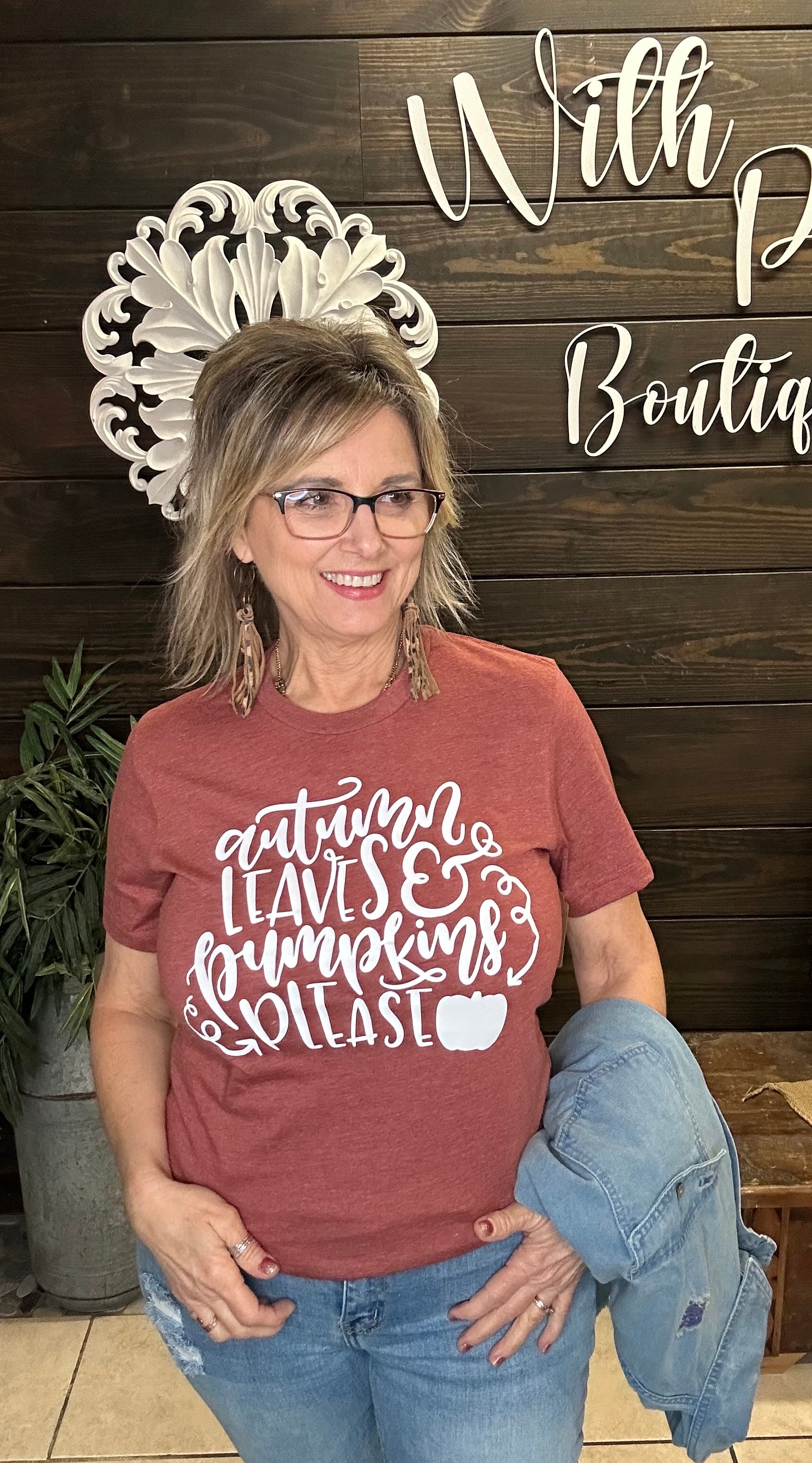 women in a graphic tee in the color of rust in front of a wooden wall