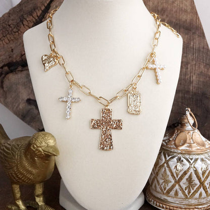 Gold necklace with various pendants on a white mannequin bust against a rustic background.