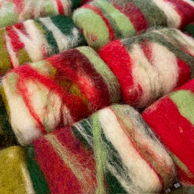 Close-up of multicolored yarn skeins with red, green, and white stripes, with sweet mint hand poured soaps inside