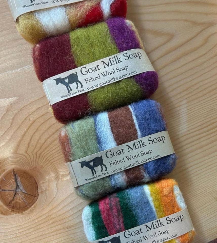 Stack of colorful goat milk soap bars on a wooden surface with 'Goat Milk Soap' label.